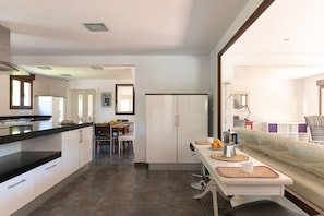 Una cocina moderna con armarios blancos, un comedor con mesa y sillas, y una sala de estar con un sofá.