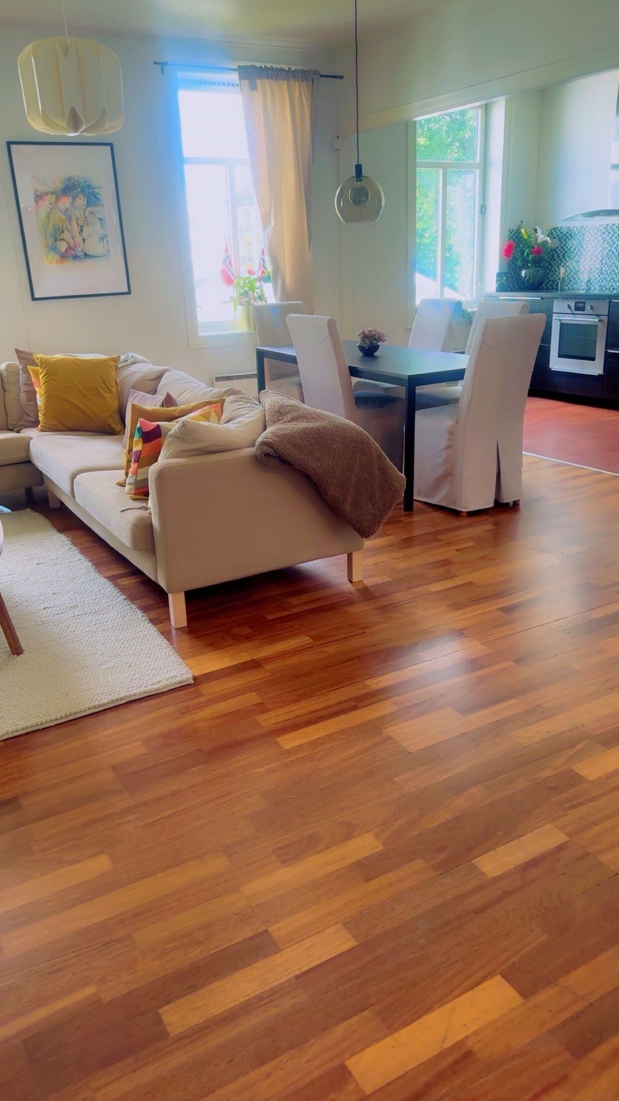 A living room with a sofa, dining table, chairs, and a kitchen area.