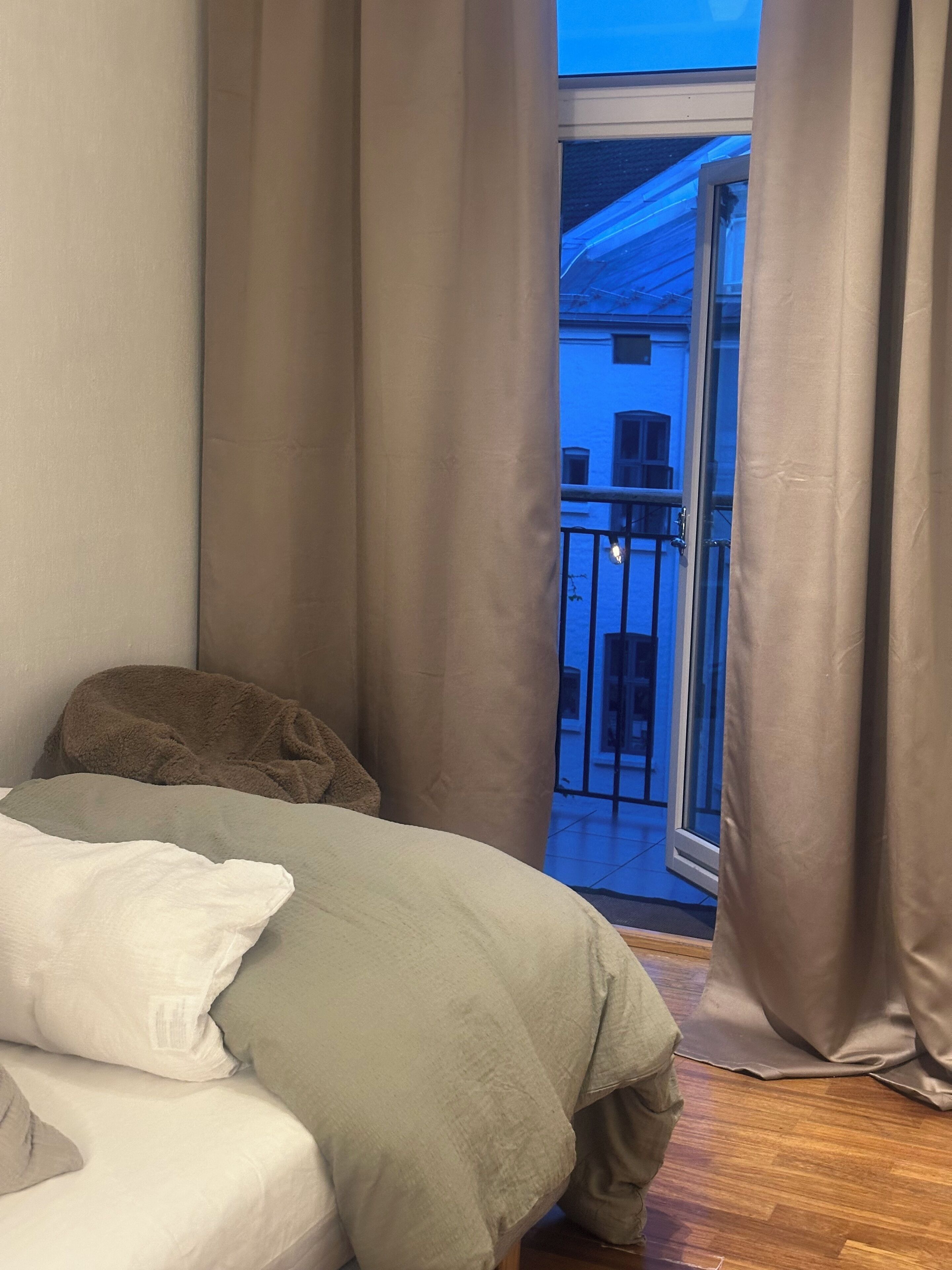 Een slaapkamer met een bed, een raam en uitzicht op een balkon.