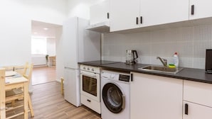 Une cuisine compacte équipée d’un lave-linge, d’une machine à café et d’un évier.