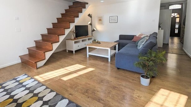 Un salon moderne avec un escalier, un canapé, une table basse et une plante en pot.