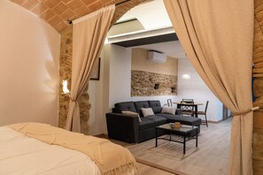 A bedroom with a bed, a sofa, a coffee table, and a dining area with a table and chairs. - Can Joan Loft - A romantic loft with a medieval arch on the Costa Brava (Ordis)