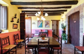 A dining area with a wooden table, chairs, a chandelier, and artwork on the walls. - Country House with Vineyard Views, BBQ & Fireplace (El Pla del Penedès)