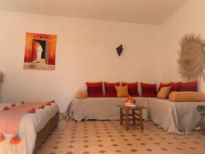 Habitació amb llit, sofà, taula petita i un quadre penjat a la paret.