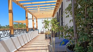 A covered outdoor area with a tiled floor, wooden pergola, potted plants, and a seating area. - Villa 6 Chambres 3 Suites, piscine chauffée. Prix 18 pax avec petits déjeuners. (Essaouira)