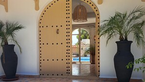A wooden arched entrance with a tiled floor leading to a pool area. - Villa 6 Chambres 3 Suites, piscine chauffée. Prix 18 pax avec petits déjeuners. (Essaouira)