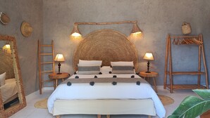 A bed with a large woven headboard, two bedside lamps, a wooden ladder, a woven basket, and a wooden rack with hangers. - Villa 6 Chambres 3 Suites, piscine chauffée. Prix 18 pax avec petits déjeuners. (Essaouira)