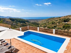Ein Pool mit Delfin-Motiv, umgeben von einer Terrasse mit Blick auf die Landschaft.