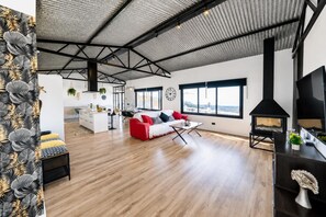 Un salón espacioso con techos altos, chimenea y ventanas grandes que ofrecen vistas.