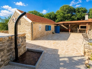 A stone building with a tiled roof, a small entrance, and a patio area with a table and chairs. - Didini Dvori - One Bedroom Villa, Sleeps 2 (Kruševo)