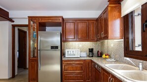 A kitchen with wooden cabinets, a stainless steel refrigerator, a microwave, a coffee maker, and a sink. - Villa Nefeli Breeze - Three Bedroom Villa, Sleeps 6 (Rethymno)