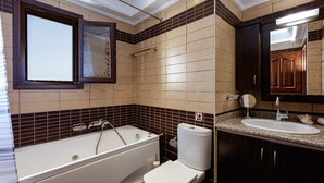 A bathroom with a bathtub, toilet, sink, and mirror. - Villa Nefeli Breeze - Three Bedroom Villa, Sleeps 6 (Rethymno)