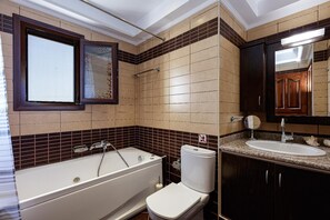Een badkamer met een bad, toilet, wastafel en spiegel.