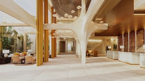 A spacious lobby with high ceilings, a reception desk, seating area, and large windows.