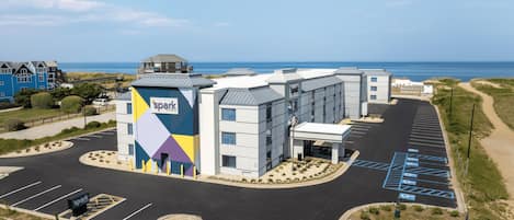 A hotel with a parking lot and a view of the sea.