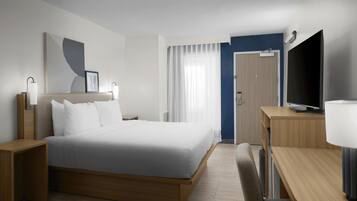 Habitación de hotel moderna con una cama grande, mesitas de noche, un escritorio con silla, televisor y una ventana con cortinas.