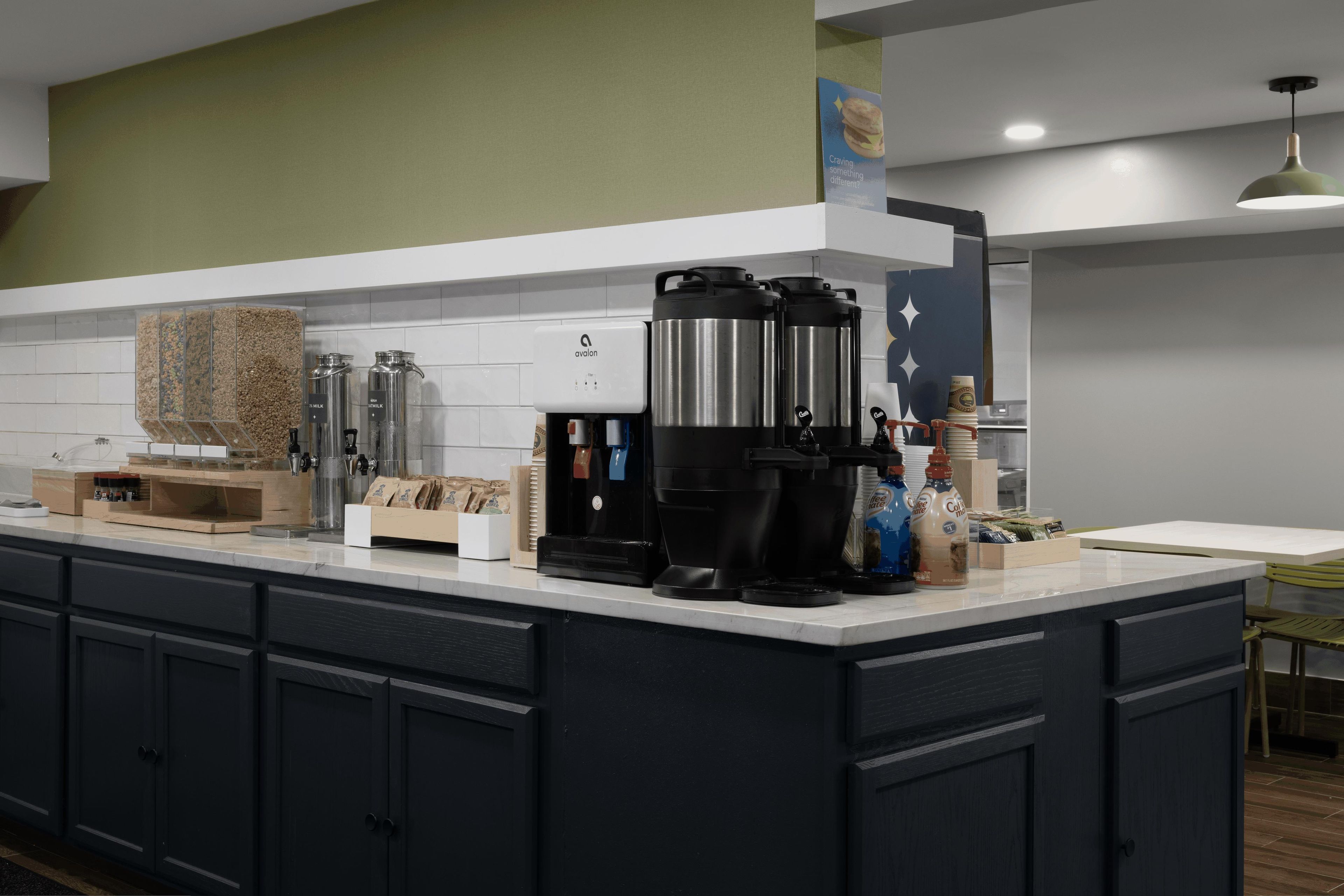 Una cocina moderna con estación de café, que incluye una cafetera, dispensadores de leche y una prensa francesa.