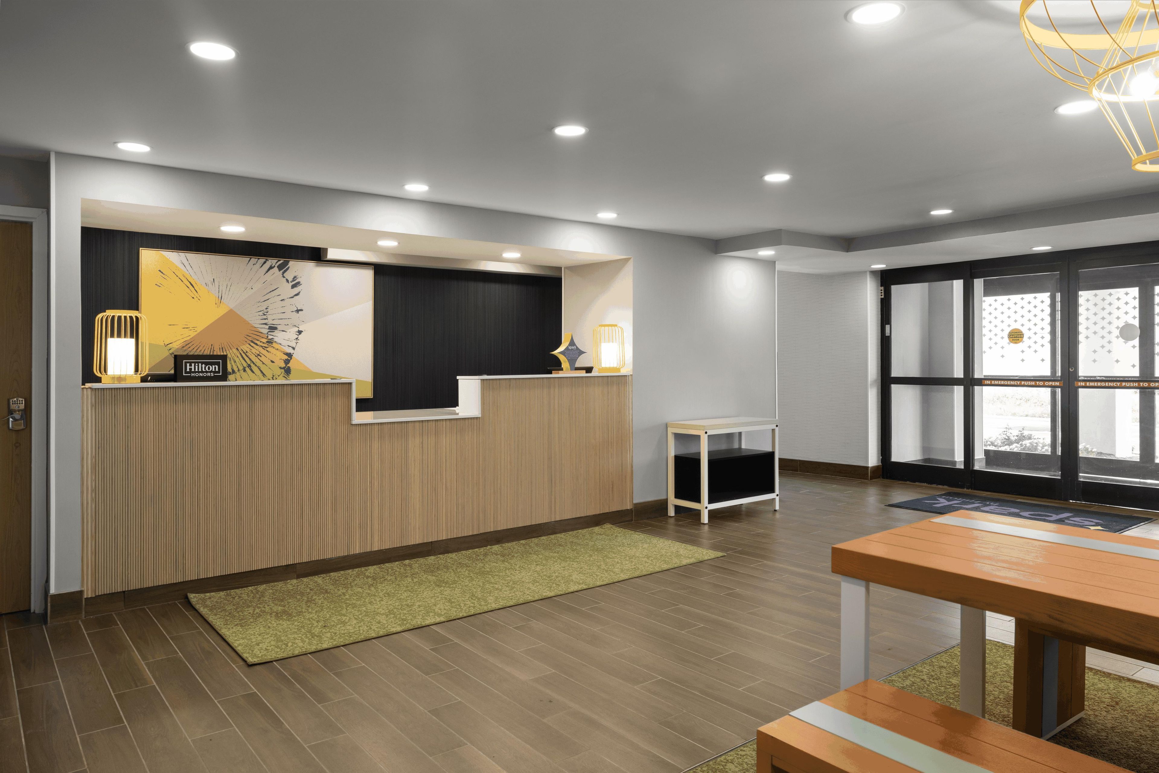 A reception area with a wooden reception desk, a small side table, and a green rug.