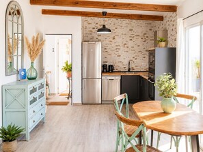 Una cucina con frigorifero, lavastoviglie e travi in legno al soffitto.