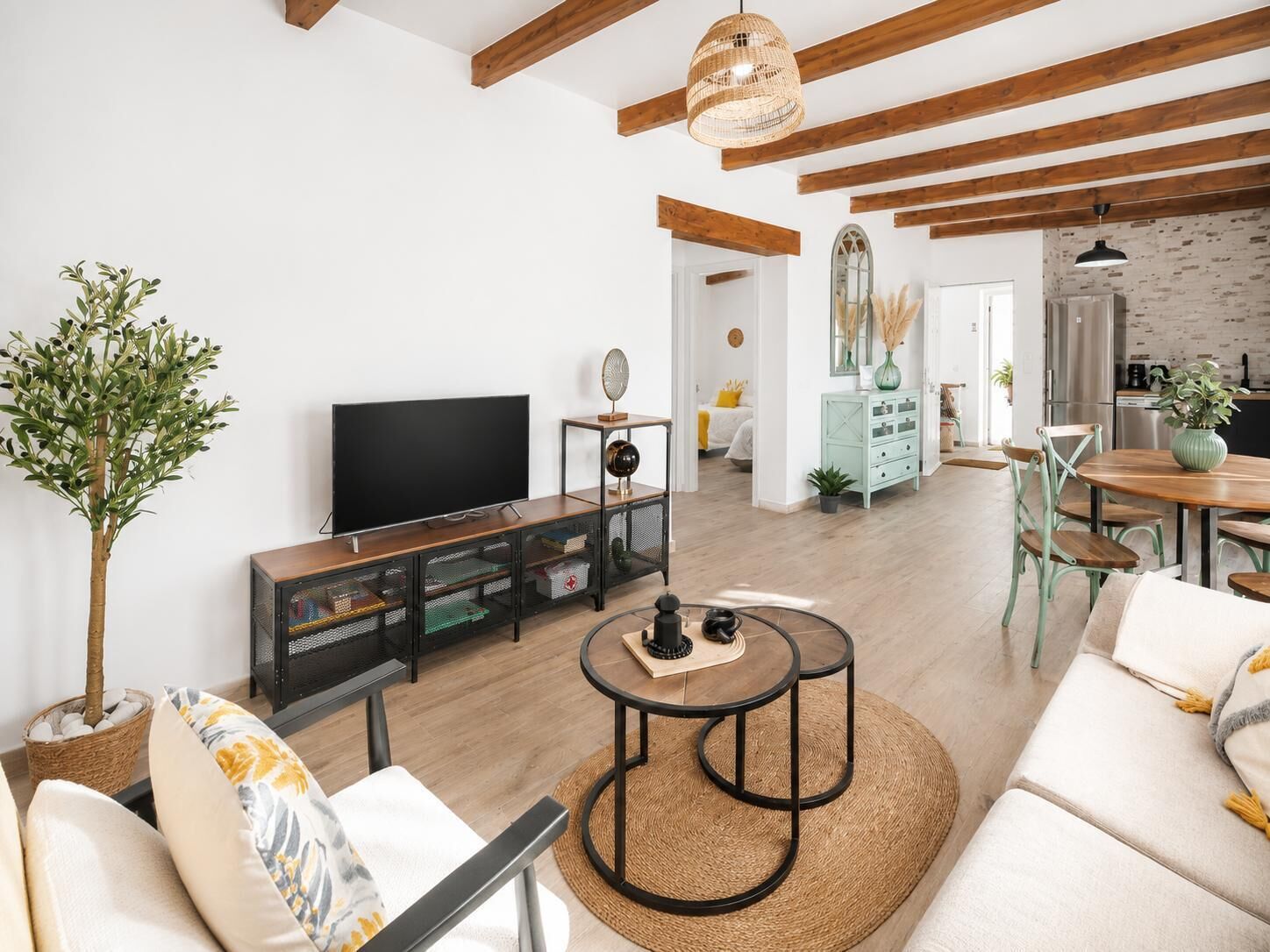 Sala de estar com televisão, sofá, mesa de centro e área de jantar com cadeiras e mesa.