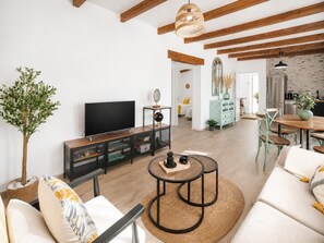Ein Wohnzimmer mit Fernseher, Sofa, Couchtisch und einem Essbereich mit Stühlen und Tisch.