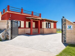 Un edificio rojo con entrada porticada, muros de piedra y cielo azul claro.