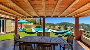 Un patio techado con piscina, sillas de descanso y una mesa.