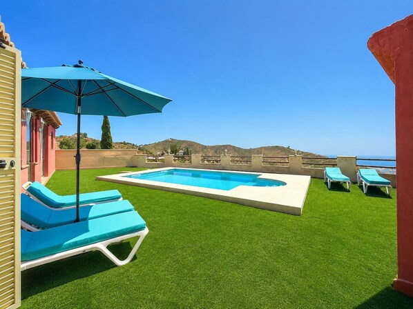 A swimming pool with a view of the ocean, surrounded by artificial grass and lounge chairs. - Villa La Casa Roja - Three Bedroom Villa, Sleeps 5 (Torrox)