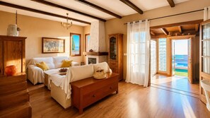 Ein Zimmer mit einer Couch, einer hölzernen Kommode, einem Kamin und Blick durch eine Glastür.