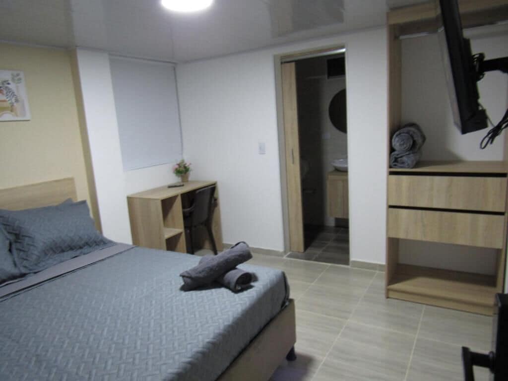 A bedroom with a bed, a desk, and a wardrobe.