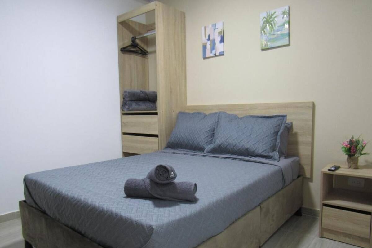 A bedroom with a bed, a wardrobe, a nightstand, and a wall with two paintings.