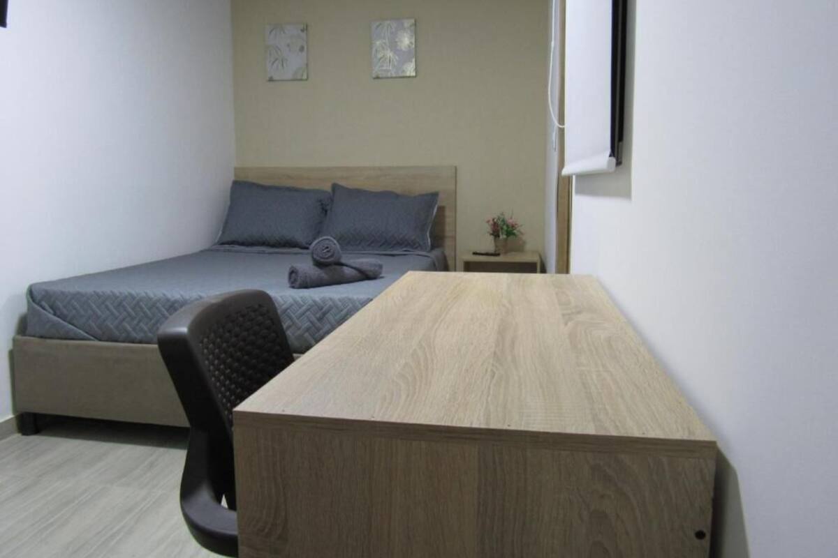 A bedroom with a bed, a desk, and two wall-mounted artworks.
