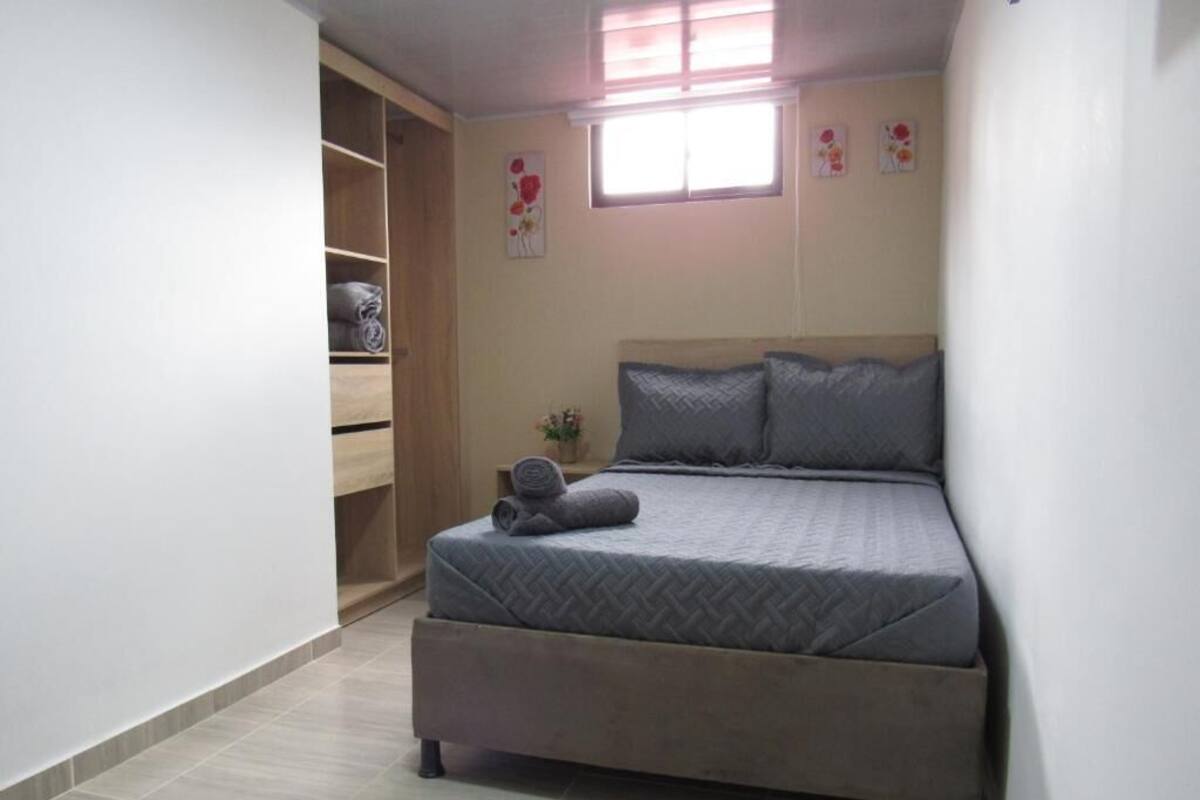 A bedroom with a bed, a wardrobe, and a window.