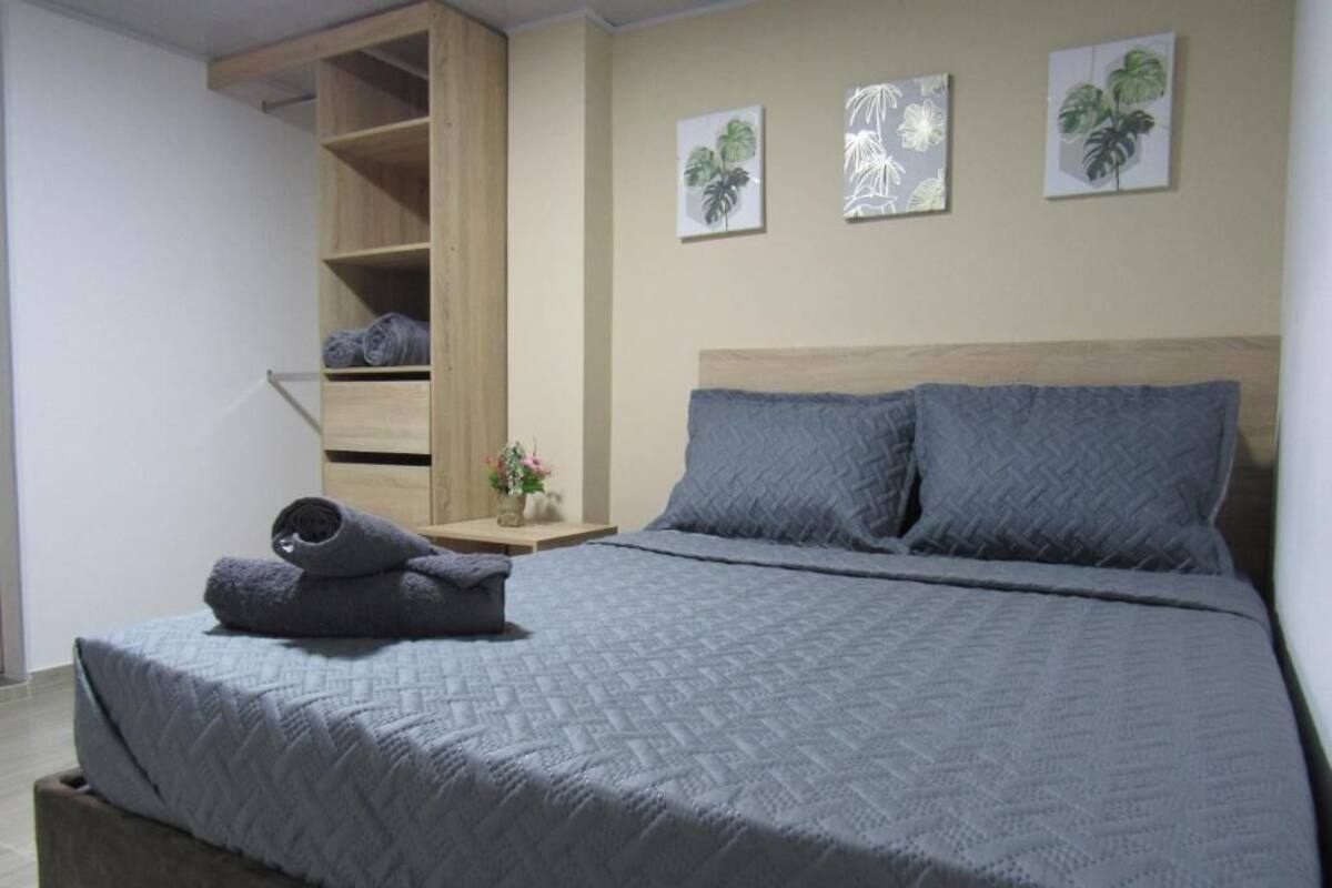 A bedroom with a bed, a wooden wardrobe, and three wall-mounted plant artworks.