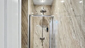 Une salle de bain moderne avec une douche en verre, des murs en marbre et un plancher en bois.