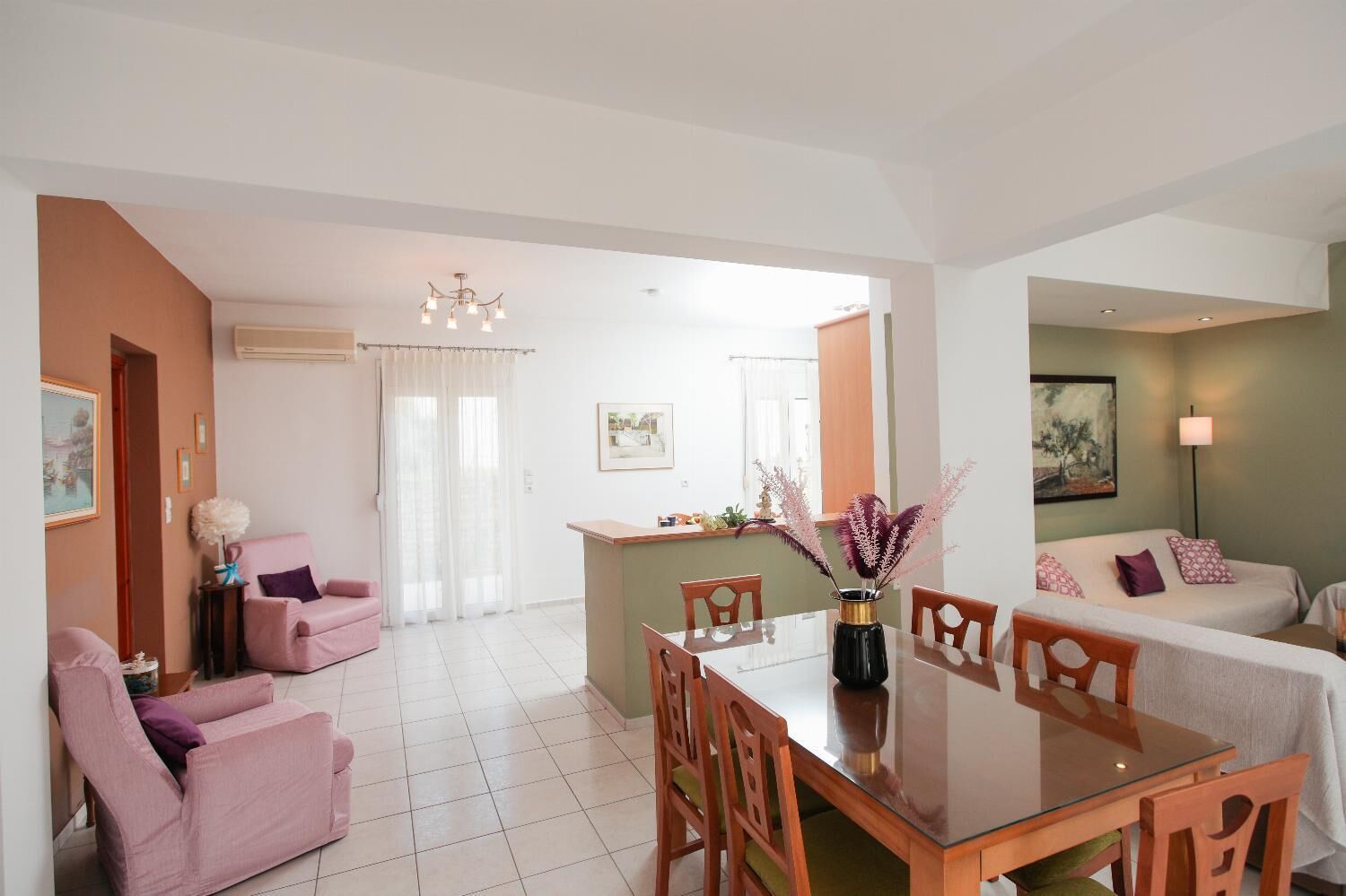 A modern living room with a dining area, a sofa set, and a kitchen in the background.