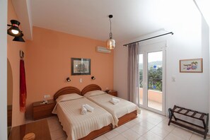 Ein Schlafzimmer mit zwei Betten, einem Balkon mit Blick und einem Deckenventilator sowie einer Wandklimaanlage.