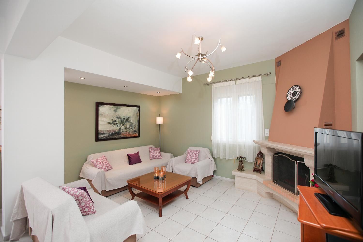 A living room with a sofa set, a coffee table, a TV, and a fireplace.