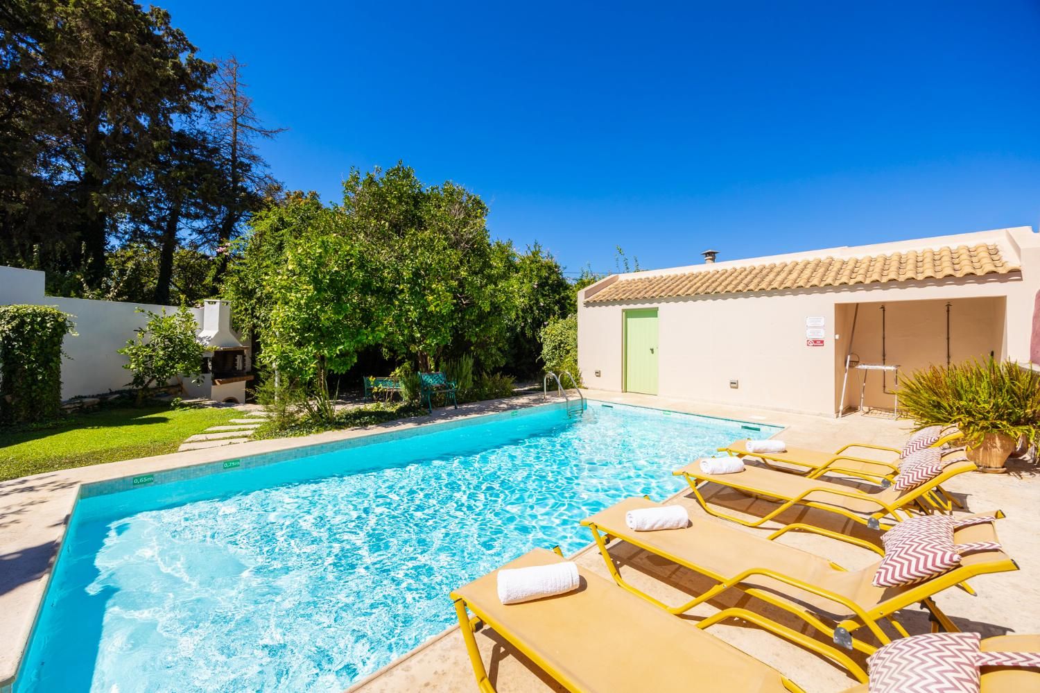 A swimming pool with lounge chairs and a barbecue area.