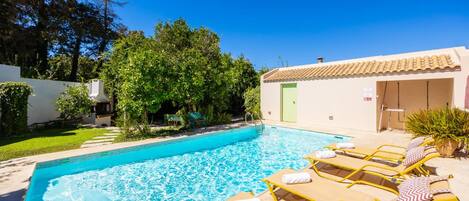 A swimming pool with lounge chairs and a barbecue area.
