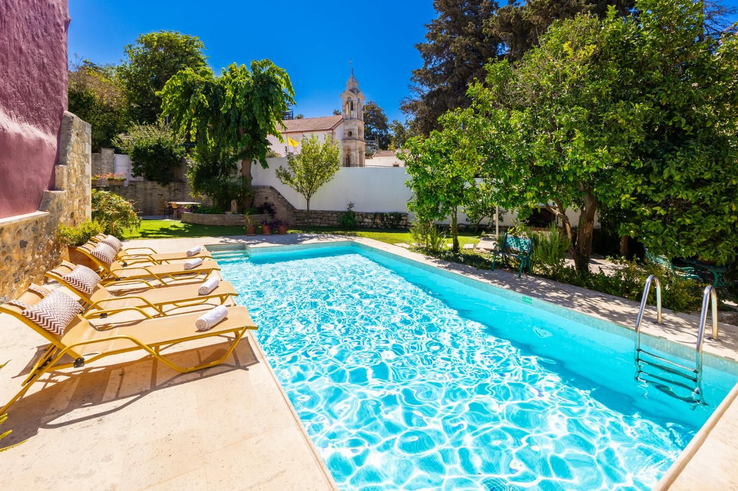 Une piscine avec des chaises longues et un mur en pierre.