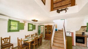 Ein Essbereich mit Holztisch und Stühlen, eine Treppe und eine Küche mit Herd.