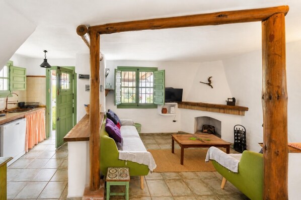 A cozy living room with a sofa, a small table, and a fireplace. - Villa El Olivarillo - Three Bedroom Villa, Sleeps 6 (Frigiliana)