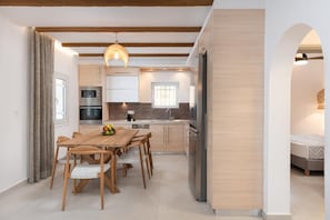 Eine moderne Küche mit Holzausstattung, einem Esstisch mit Stühlen und einem Kühlschrank.
