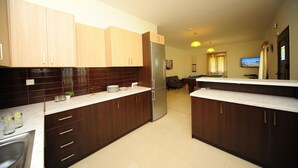 Una cocina moderna con armarios de madera oscura, un refrigerador de acero inoxidable y un comedor con mesa de billar.
