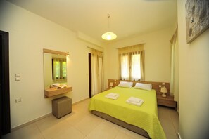 Une chambre d’hôtel comprenant un lit, une table de chevet, un miroir, une fenêtre avec des rideaux et un luminaire.