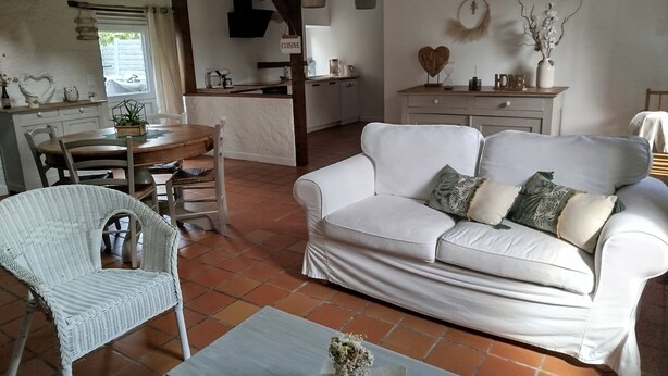 A cozy living room with a white sofa, a dining table, and a kitchen area. - A vacation rental in the heart of Morbihan, nestled between land, river, and ocean! A guaranteed chance to recharge! (Saint-Dolay)