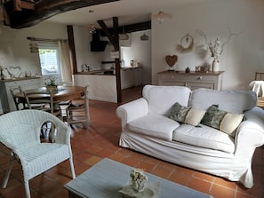 A cozy living room with a white sofa, a dining table, and a kitchen area. - A vacation rental in the heart of Morbihan, nestled between land, river, and ocean! A guaranteed chance to recharge! (Saint-Dolay)