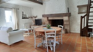 A living room with a fireplace, white walls, a dining table with chairs, a sofa, and a TV. - A vacation rental in the heart of Morbihan, nestled between land, river, and ocean! A guaranteed chance to recharge! (Saint-Dolay)