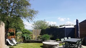 A backyard with a wooden deck, a table with chairs, a covered patio area, and a fenced garden. - A vacation rental in the heart of Morbihan, nestled between land, river, and ocean! A guaranteed chance to recharge! (Saint-Dolay)
